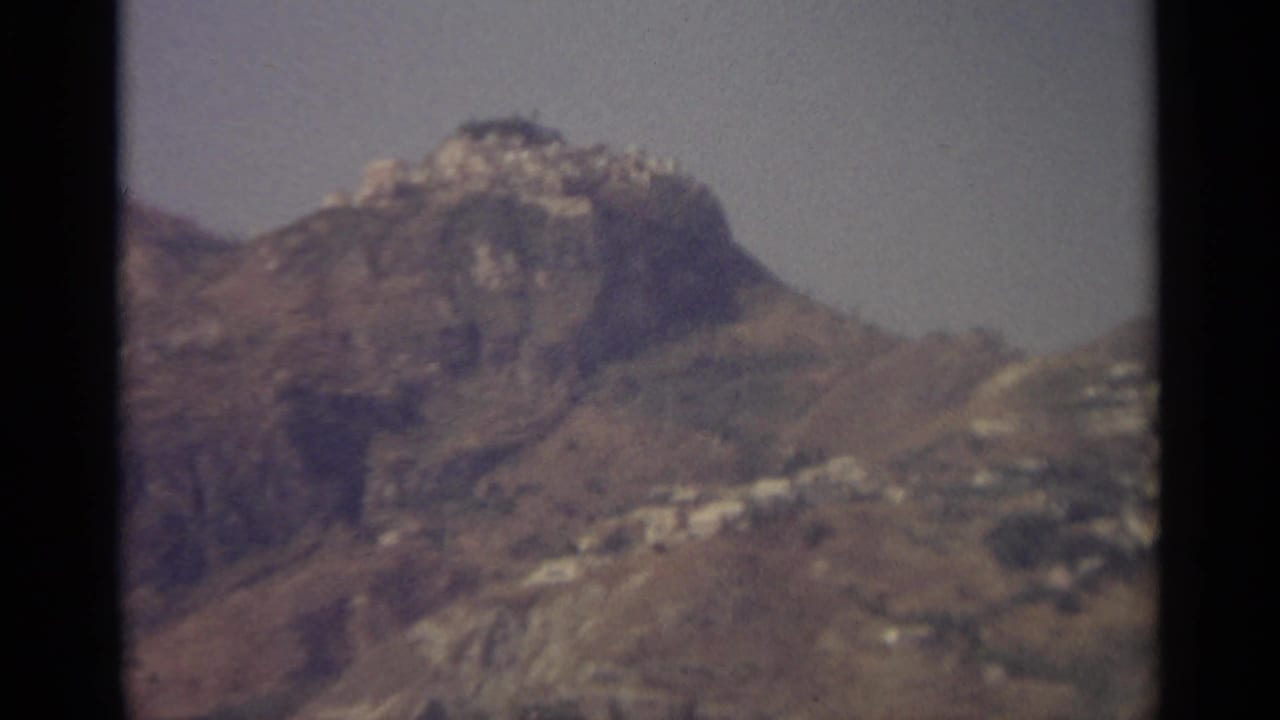 Distant rocky mountain with pale buildings scattered on the hillside.