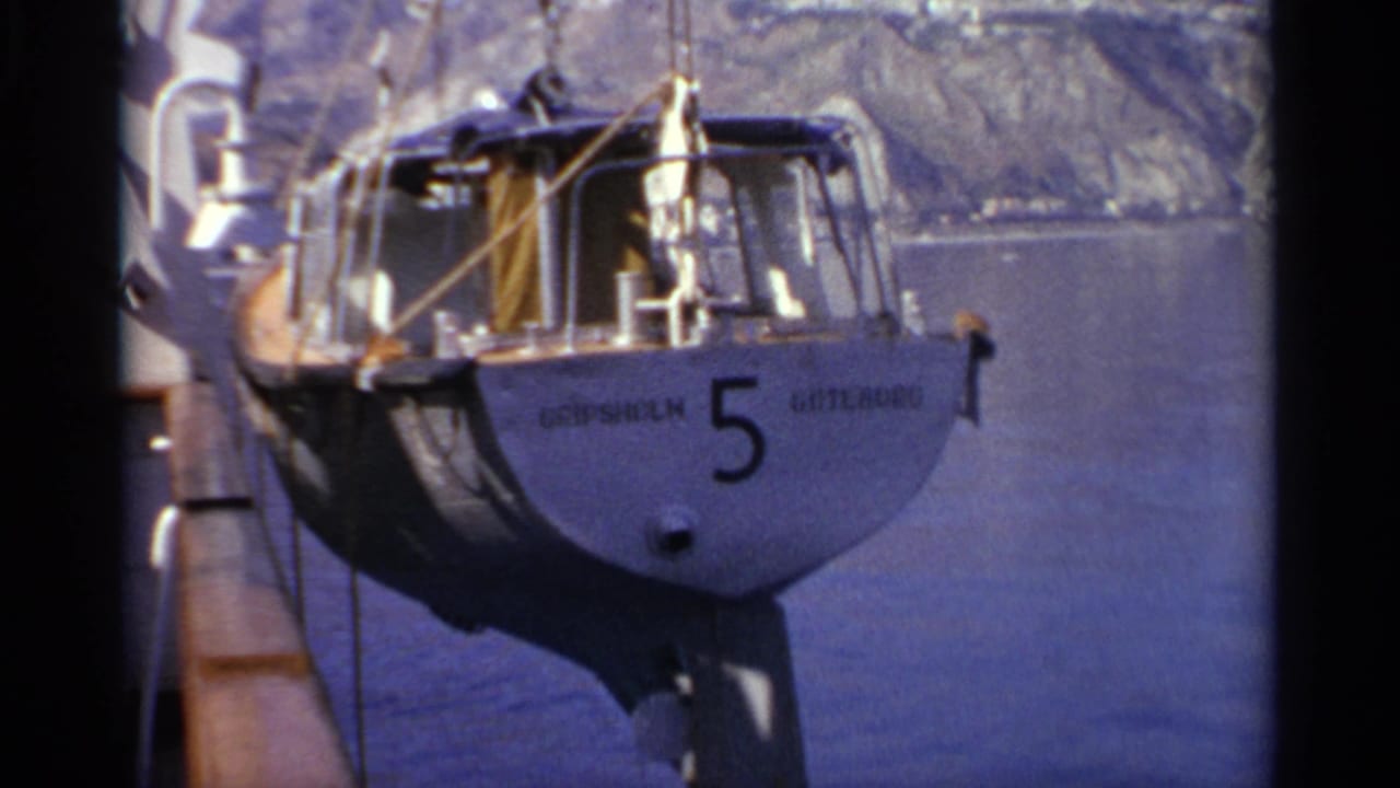 Hoisted small sailboat with number 5 is suspended over water near a ship side.