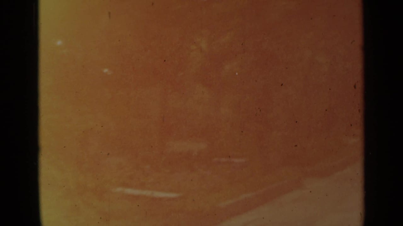 Soft, yellow-shifted 8mm frame from the Stockholm reel with little distinct subject detail visible.