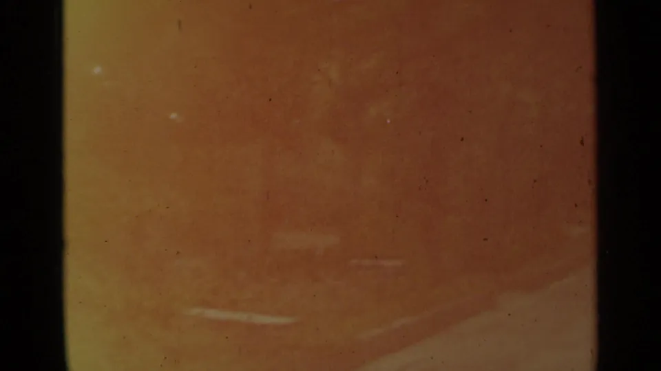 Soft, yellow-shifted 8mm frame from the Stockholm reel with little distinct subject detail visible.