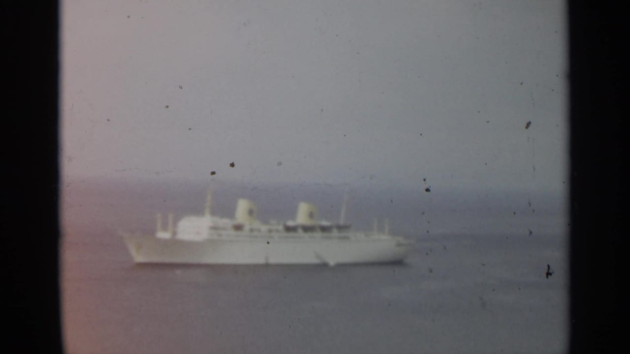 1965 8mm view near Stockholm showing a white passenger ship at sea beneath a muted, cloudy horizon.