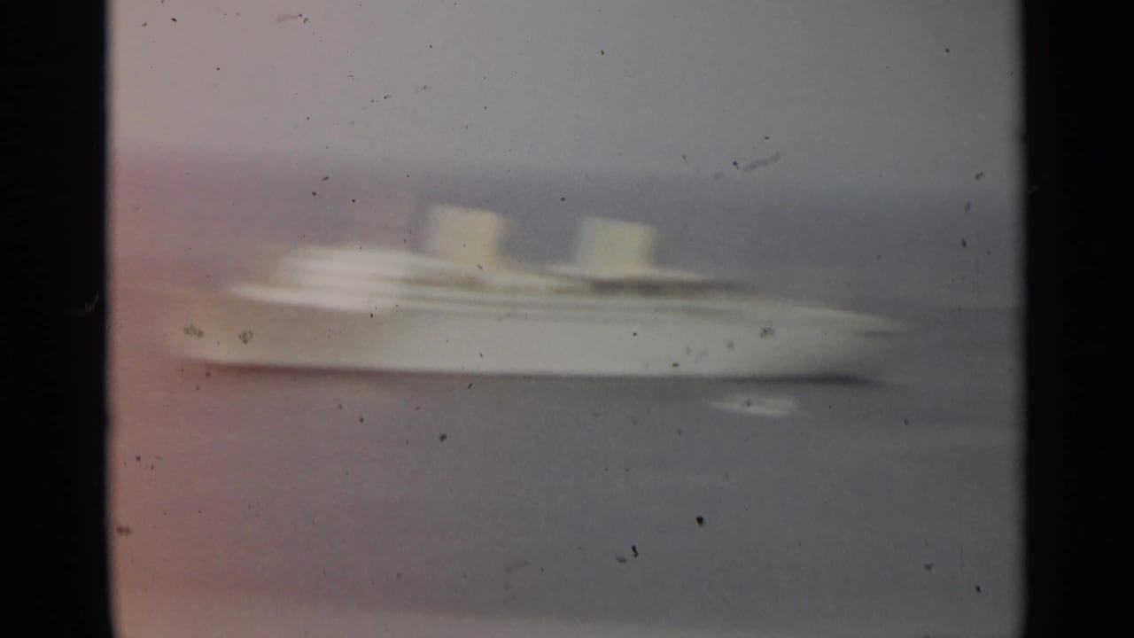 Blurred white passenger ship moving across hazy water.