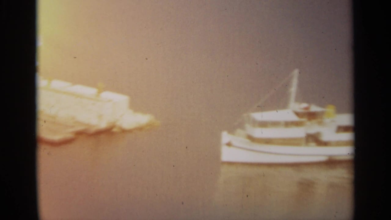 Passenger boat near a pale stone pier and calm water.