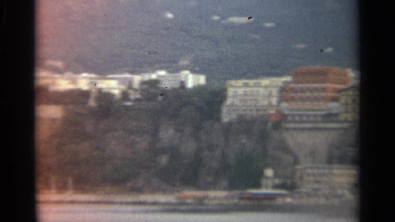 Distant Stockholm waterfront with soft buildings along the shore and water in the foreground.