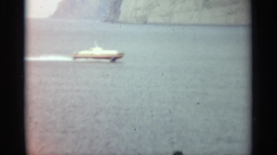 A white-and-red hydrofoil moves across Stockholm water in a soft, grainy 1965 8mm frame.