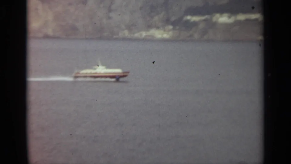 The speedboat continues across Stockholm waters, with its pale wake trailing behind and a muted shoreline beyond.