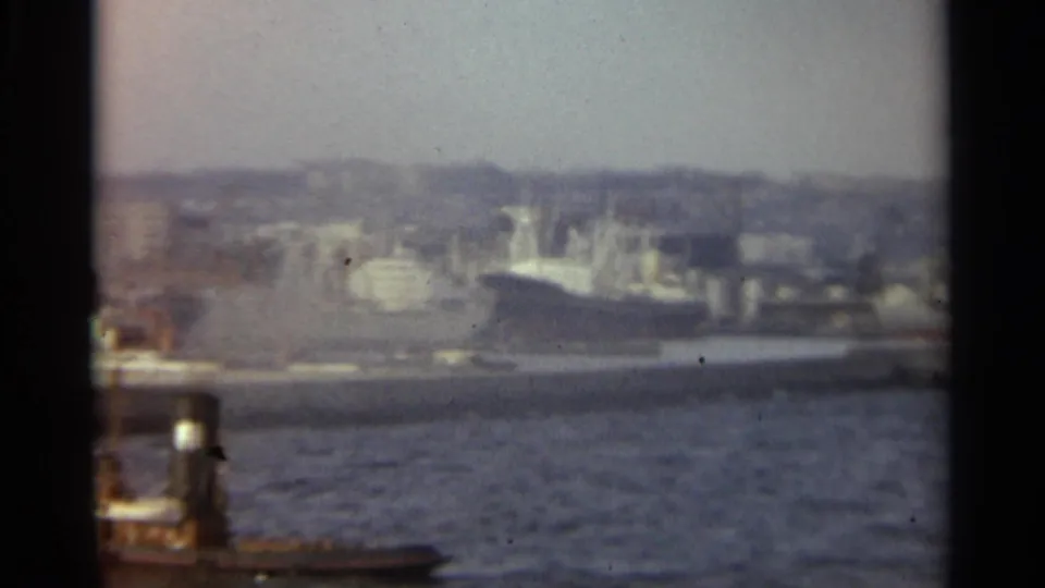 1965 Stockholm harbor view with rippled water, docked vessels, waterfront buildings, and distant hills in soft color 8mm.