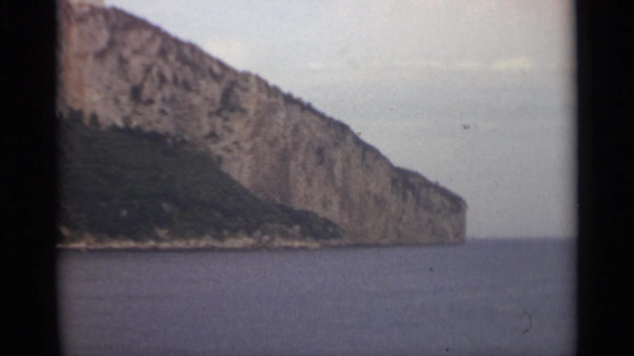 Cliff face extending into open water beneath a pale sky.