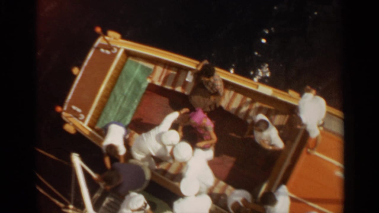 Overhead 8mm view of a yellow boat in Stockholm with passengers standing and bending near the dock edge.