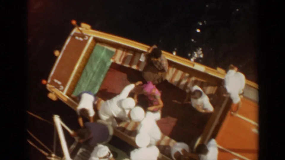 Overhead 8mm view of a yellow boat in Stockholm with passengers standing and bending near the dock edge.