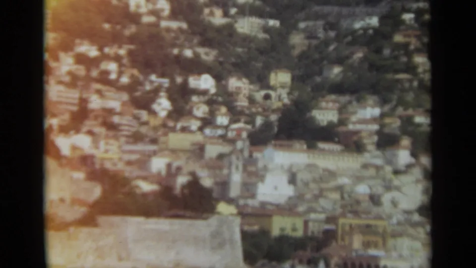 1965 Stockholm 8mm frame with an overhead view across dense buildings and trees, partly obscured by a pale foreground edge.
