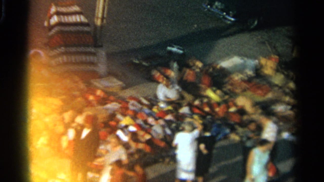 Crowded pavement market with goods laid out and shoppers gathered in warm light.