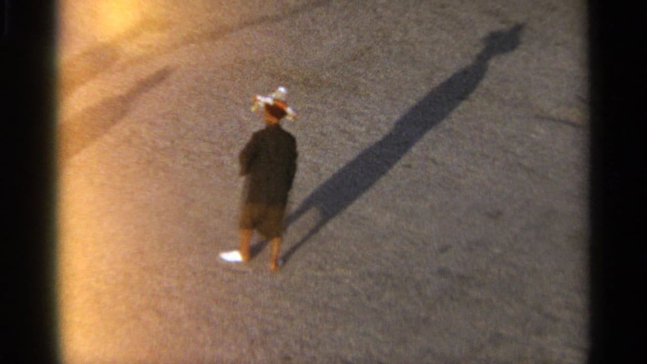 Tangier, Morocco 1965 frame of a lone pedestrian in dark clothing and a light hat crossing open pavement with a long afternoon shadow.