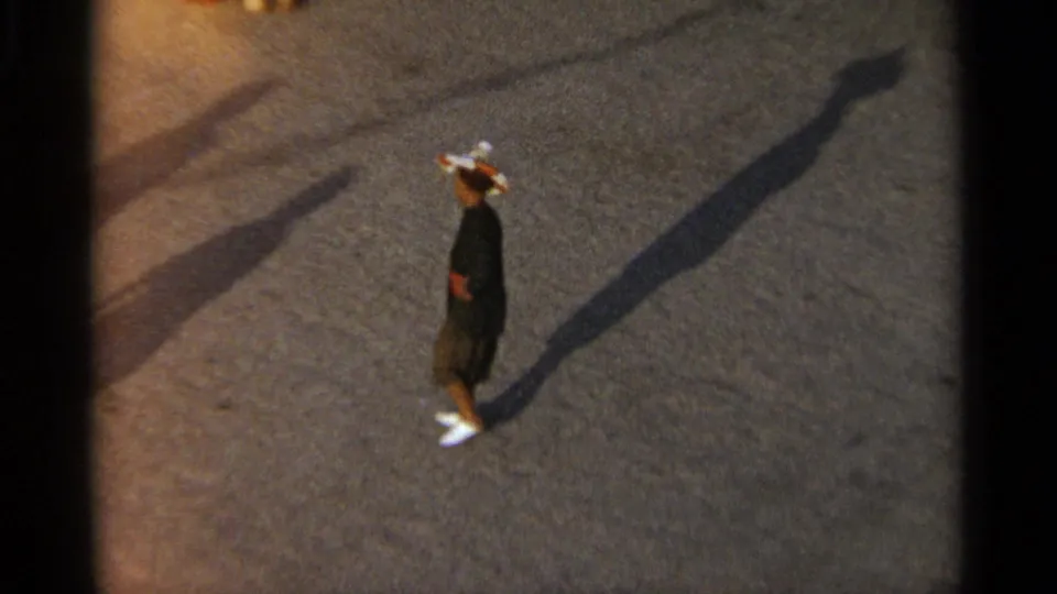 Tangier, Morocco 1965 home-movie frame of a man in dark clothing on open pavement, his shadow stretching across the frame.