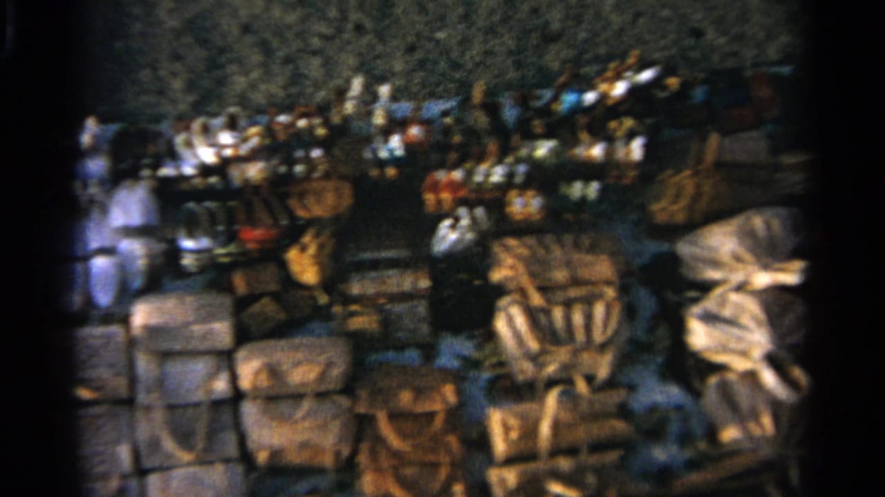 Tangier market stall seen in a wider 8mm frame, with leather bags lined along the lower edge and mixed goods behind them.