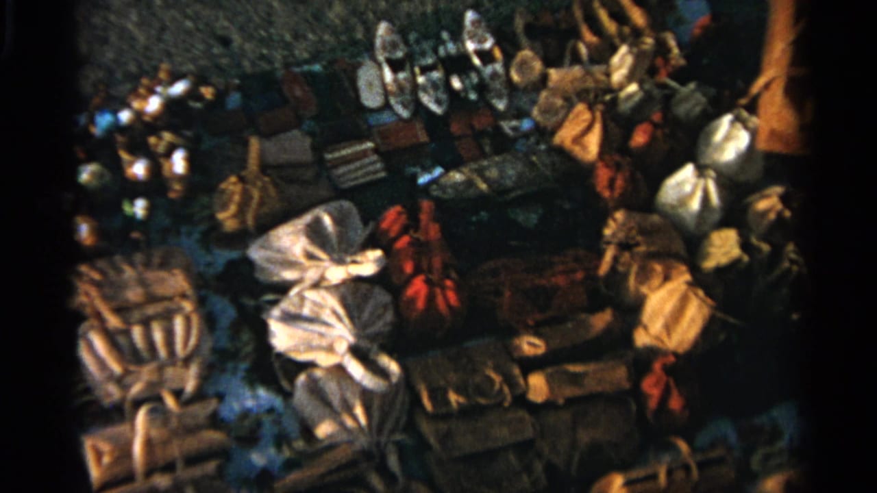 Overhead view of market goods laid on the ground, including shoes, bags, and textiles.