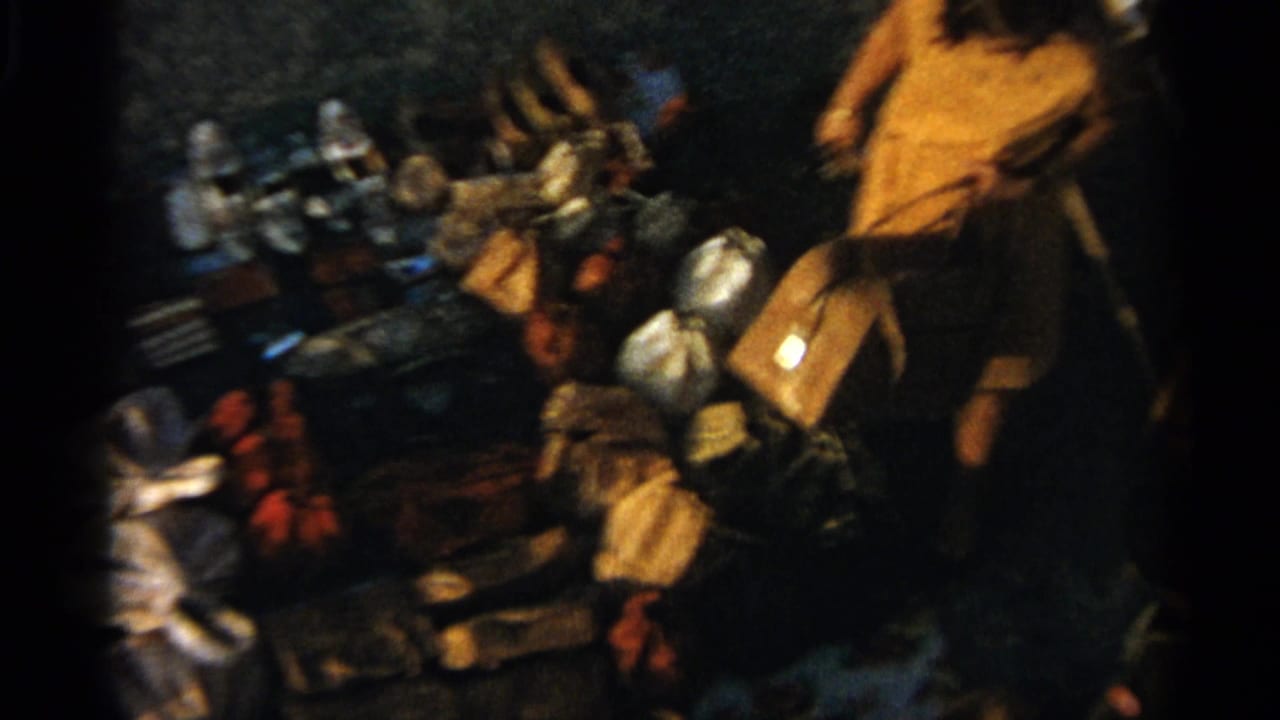 Tangier, Morocco, 1965 frame with a person in a yellow garment standing beside ground-laid market wares and bags.