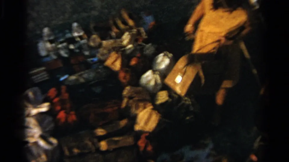 Tangier, Morocco, 1965 frame with a person in a yellow garment standing beside ground-laid market wares and bags.