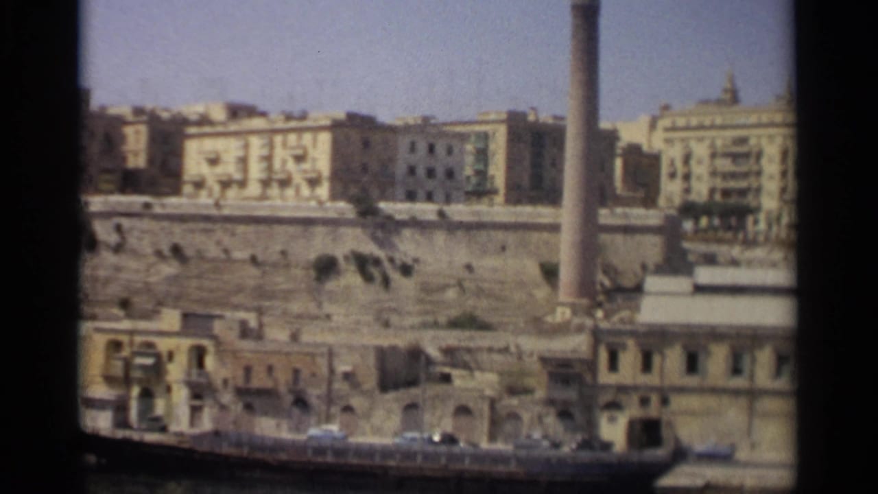 Waterfront buildings above a stone embankment with a boat at the edge.