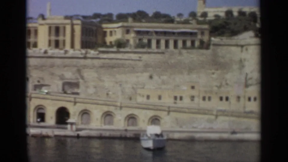 1965 Tangier waterfront with an arched doorway in the stone embankment, parked vehicles, and a small boat near the quay.