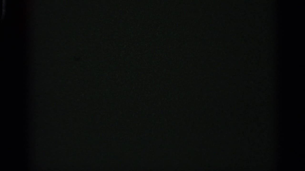 Dark final frame from the 8mm clip, with little visible subject detail beyond faint film grain and exposure falloff.