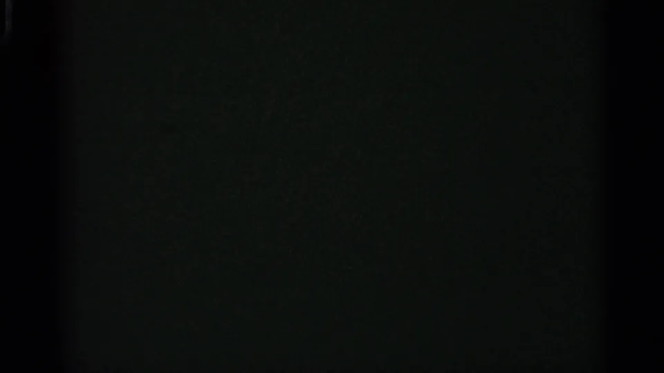 Dark final frame from the 8mm clip, with little visible subject detail beyond faint film grain and exposure falloff.
