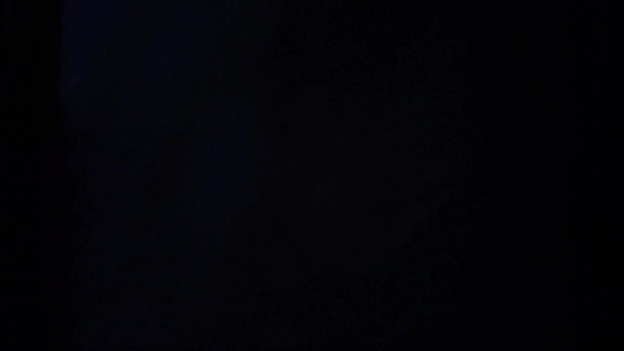 A dark transitional 8mm frame with only faint port-scene detail visible, likely from the camera pan or exposure shift.