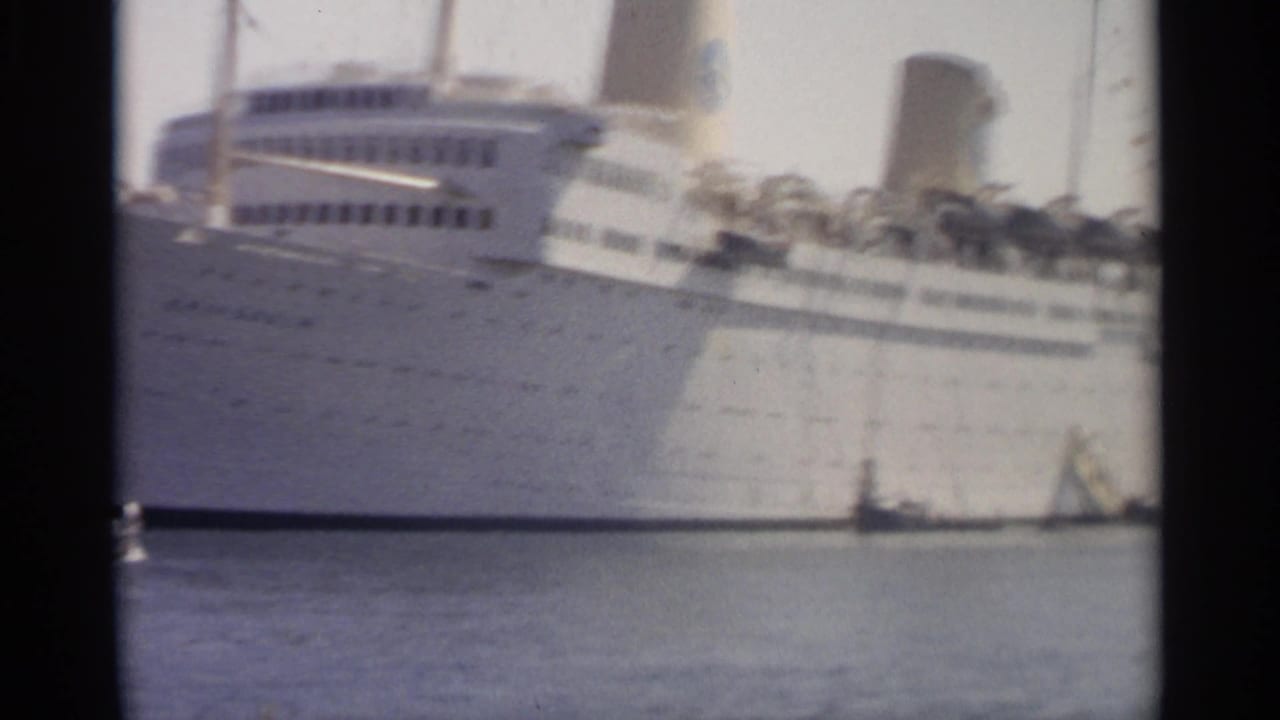 1965 Tangier harbor view of a white passenger ship's side, funnel, portholes, and a small craft near the waterline.