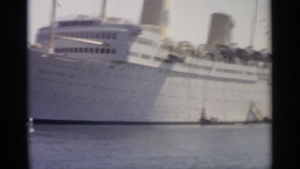 1965 Tangier harbor view of a white passenger ship's side, funnel, portholes, and a small craft near the waterline.