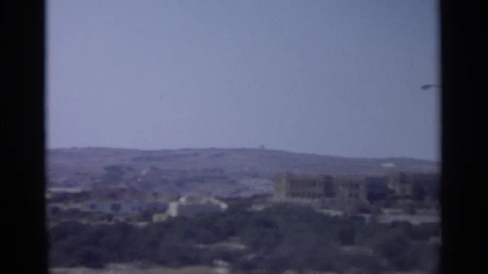 1965 Tangier view with a central window divider framing hazy hills and low urban buildings in the distance.