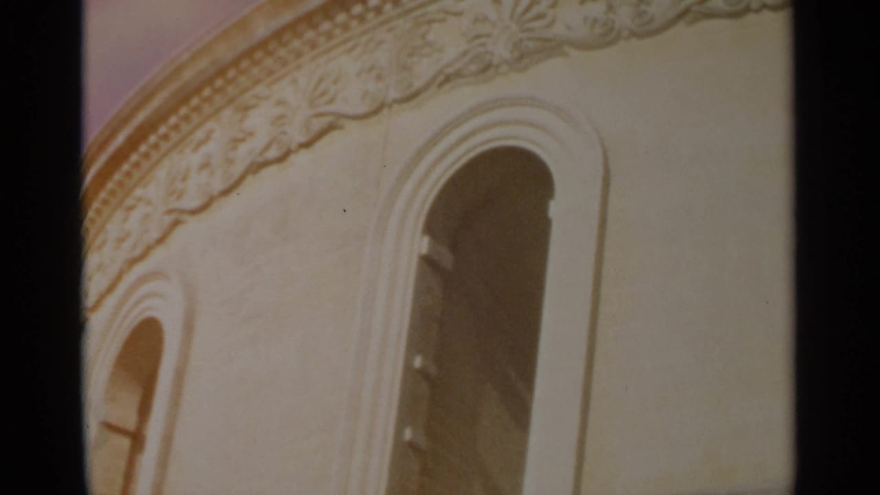 Ornate pale building facade with arched windows and decorative cornice.