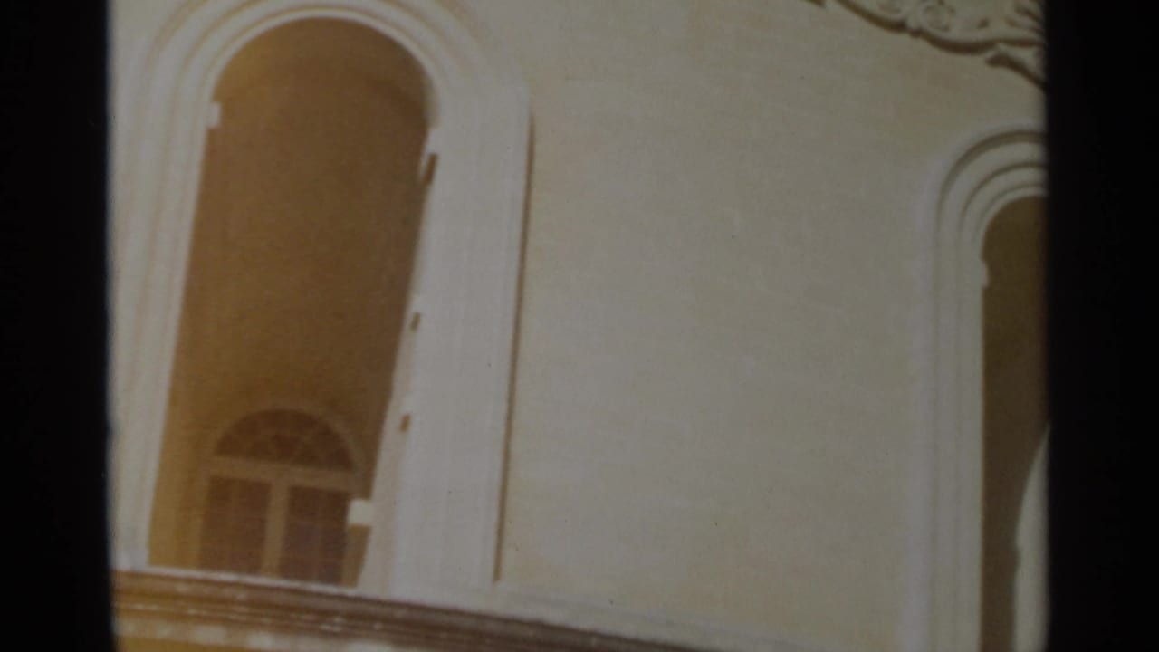 1965 Tangier frame showing an arched window, pale ornate wall, balcony edge and decorative trim near the frame corner.