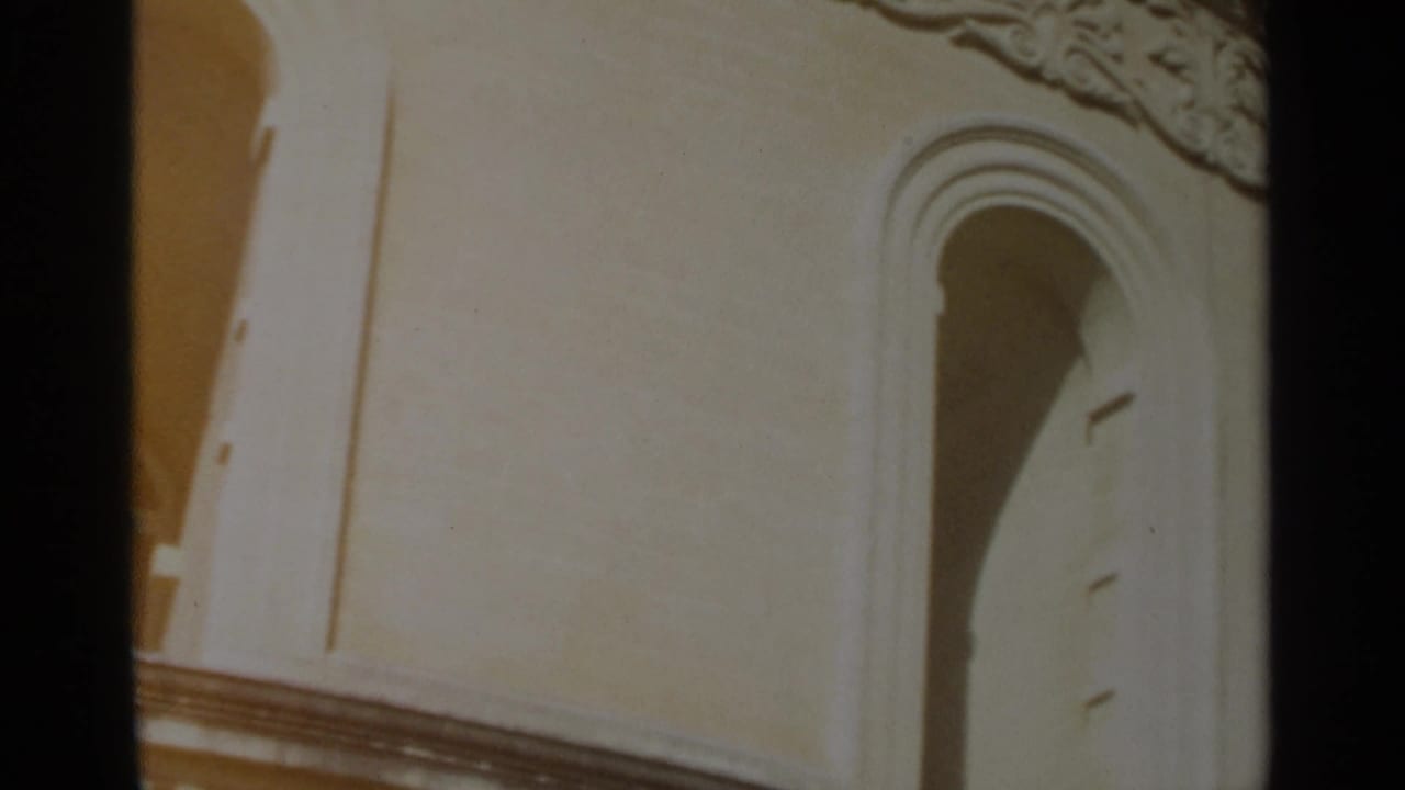 1965 Tangier home-movie frame showing a close view of cream church stonework with arched openings and decorative upper trim.