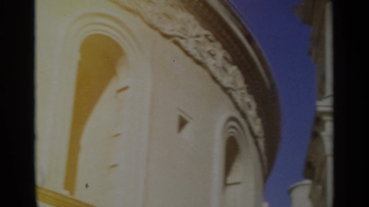 Curved church tower wall with arched opening, decorative trim and blue sky.