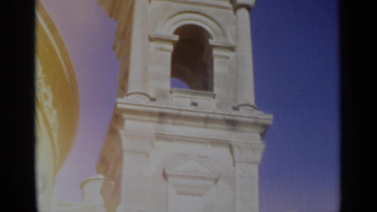 1965 Tangier home-movie view of the church bell tower facade, showing an arched opening, column details and blue sky.
