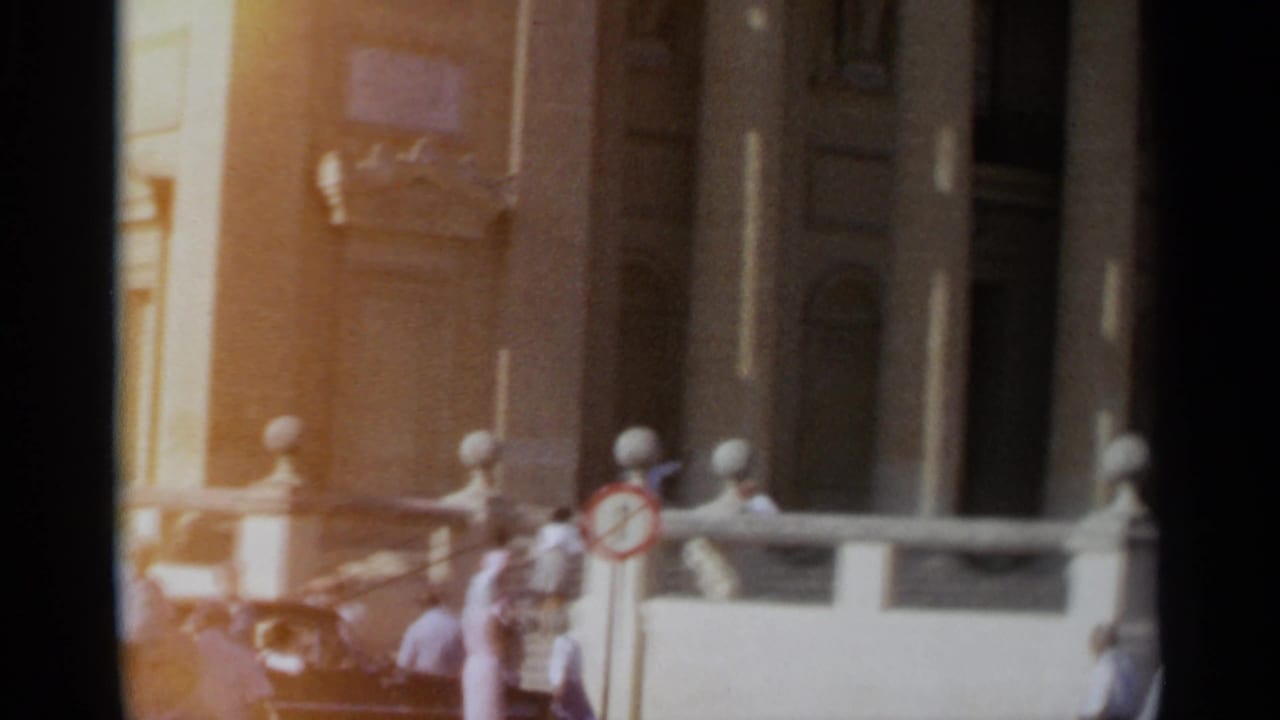 1965 Tangier frame showing the church entrance area with columns, stone bollards and several distant people near the doorway.