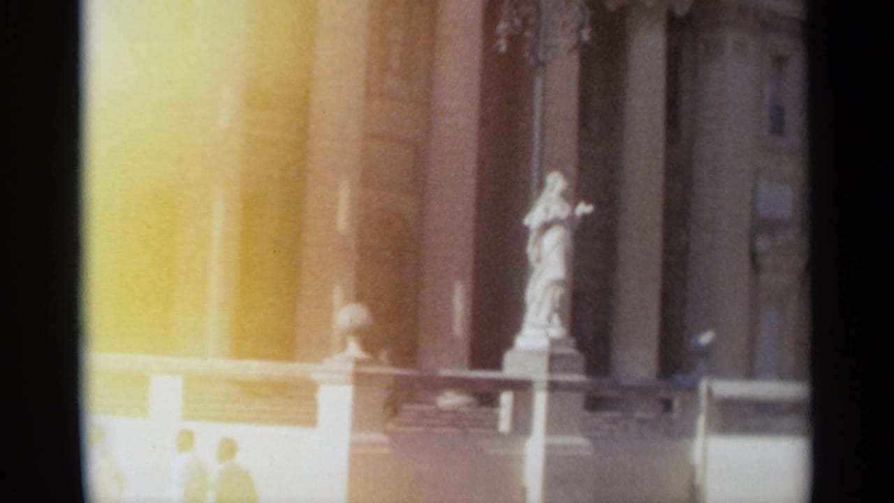 1965 Tangier frame with a classical statue near tall columns and a pale balustrade, partly obscured by warm exposure flare.