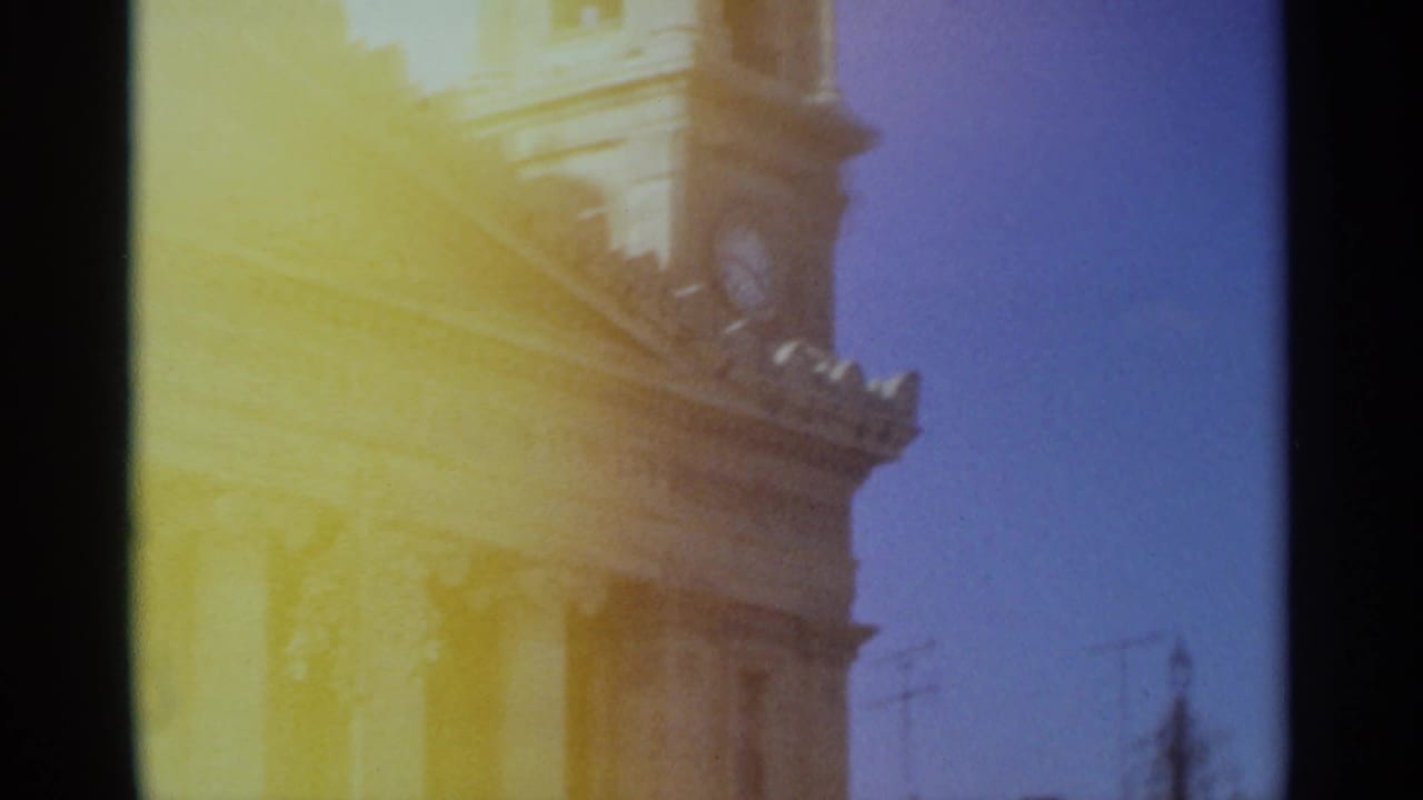 1965 Tangier frame with the building's upper facade and clock tower partly obscured by strong yellow 8mm light flare.