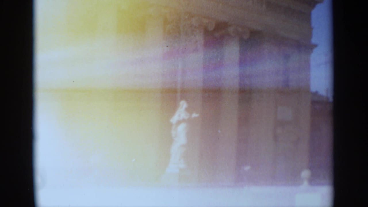 1965 Tangier frame showing the statue and classical facade softened by heavy yellow-purple 8mm exposure bloom.