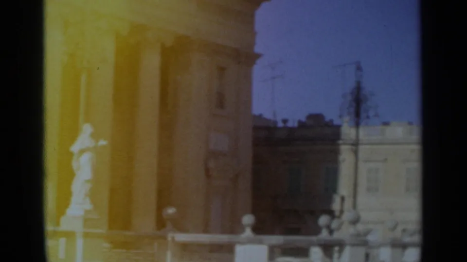 1965 Tangier frame with a pale statue set against columns, tan masonry, street lamps, and a light building across the street.