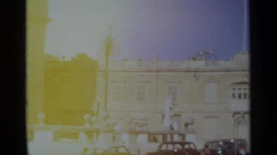 1965 Tangier street-facing frame showing pale building facades, vertical lamps, low railings, and cars in harsh sunlight.