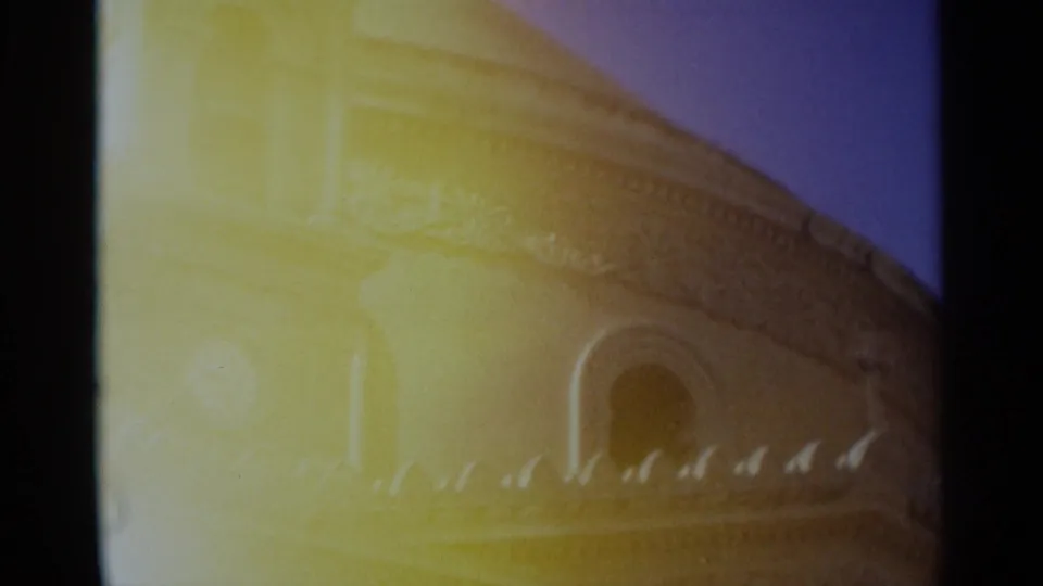 1965 Tangier home-movie frame of an ornate tan building edge, arched opening, roofline detail, and strong yellow flare.