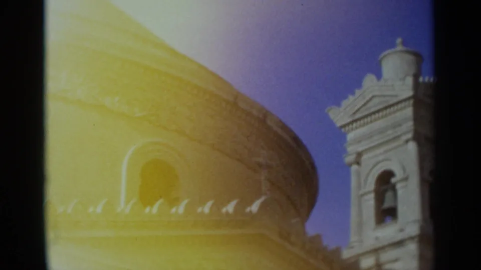1960s 8mm frame of a domed church and adjacent bell tower, filmed from below with strong color shift and soft focus.