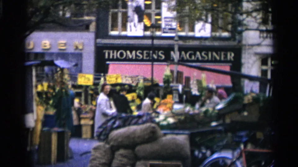 1966 Copenhagen street-market view with produce stands, shoppers, sacks, parked bicycles, and the THOMSENS MAGASINER sign visible behind them.