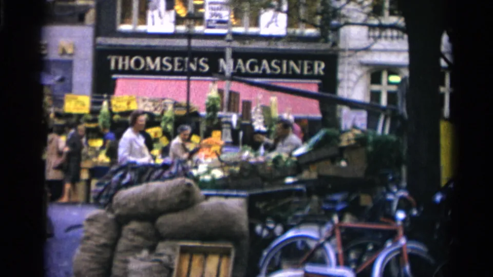 Copenhagen outdoor market scene from 1966 showing vendors, shoppers, produce displays, bicycles, and the THOMSENS MAGASINER storefront.