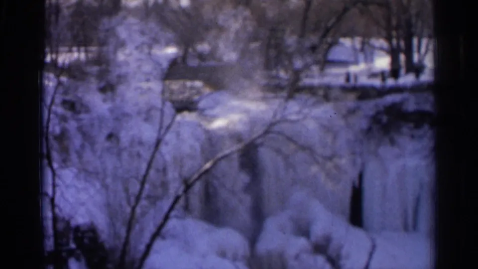 Final 8mm frame shows the snowy Minnehaha Falls and creek area in winter, with ice on the falls and bare trees across the view.