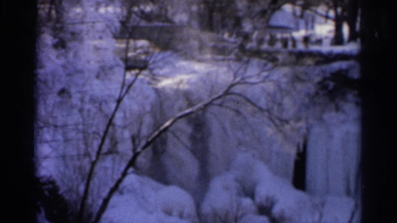 1966 Hamel, Minnesota 8mm frame showing an icy waterfall with snow-covered banks, bare branches, and darkened film borders.
