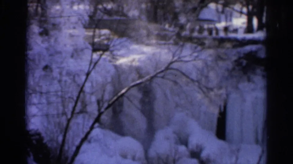 1966 Hamel, Minnesota 8mm frame showing an icy waterfall with snow-covered banks, bare branches, and darkened film borders.