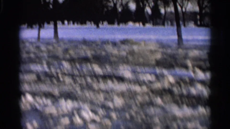 1966 Hamel, Minnesota home-movie frame showing a snowy open field with bare trees and dark frame edges.