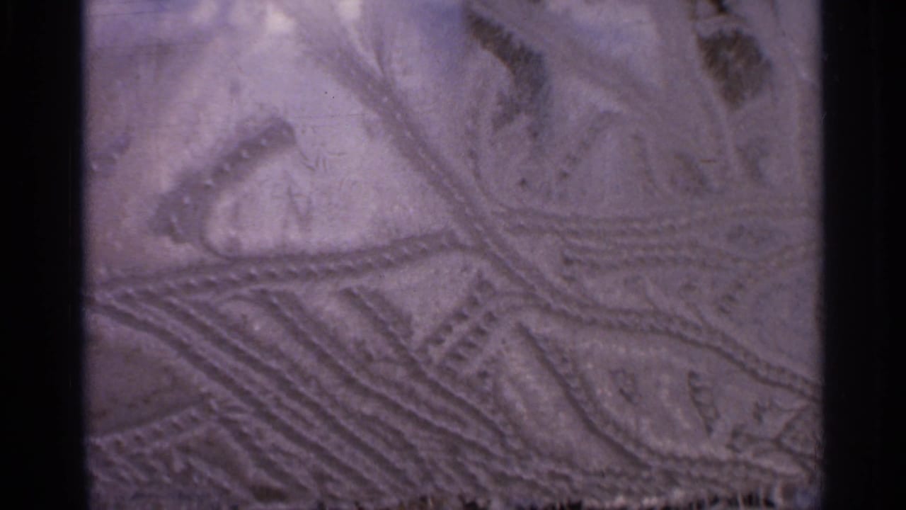 Close-up of similar carved lines and textured markings in soft purple light.